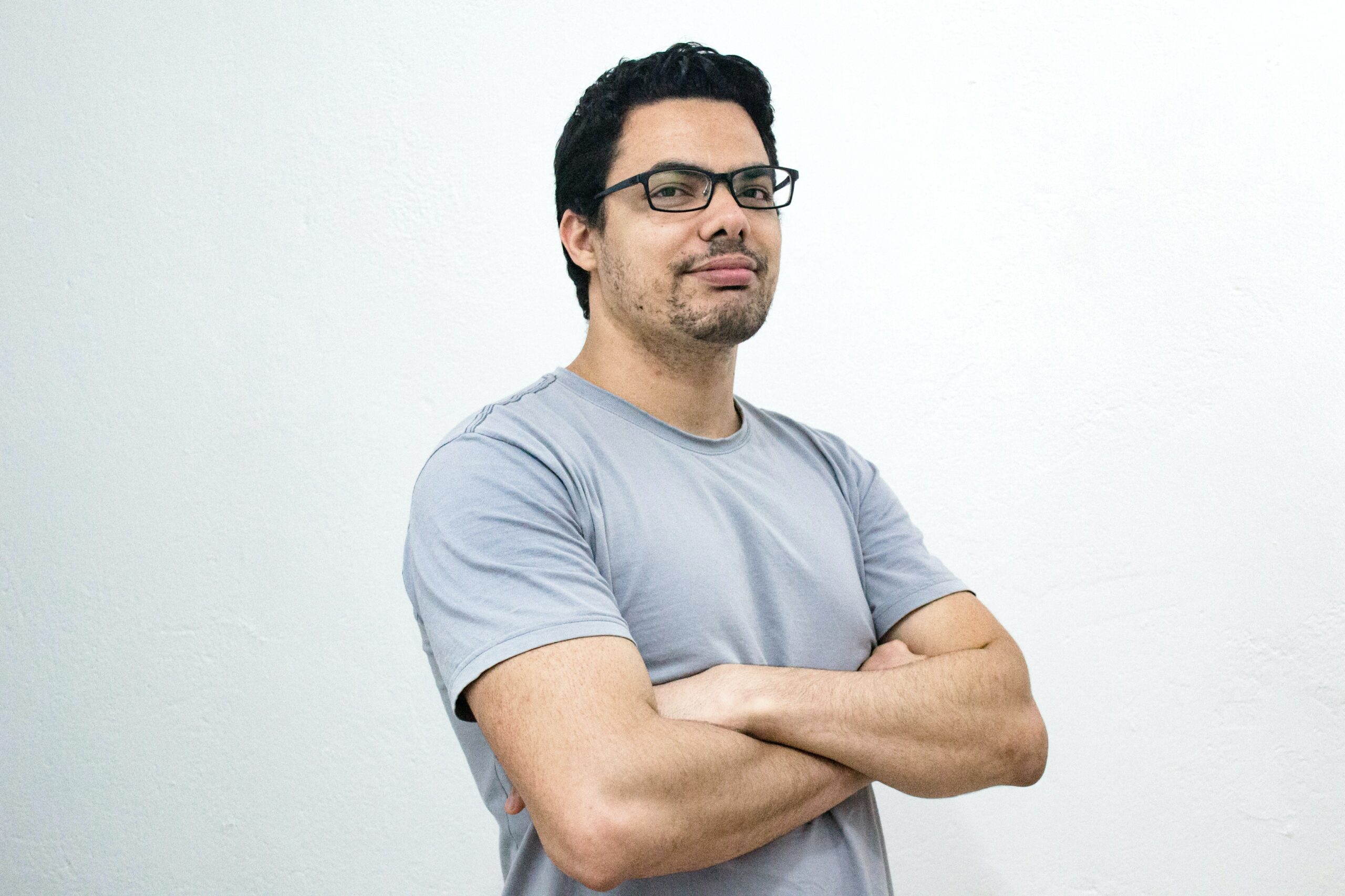 a man with his arms crossed with a grey tshirt on