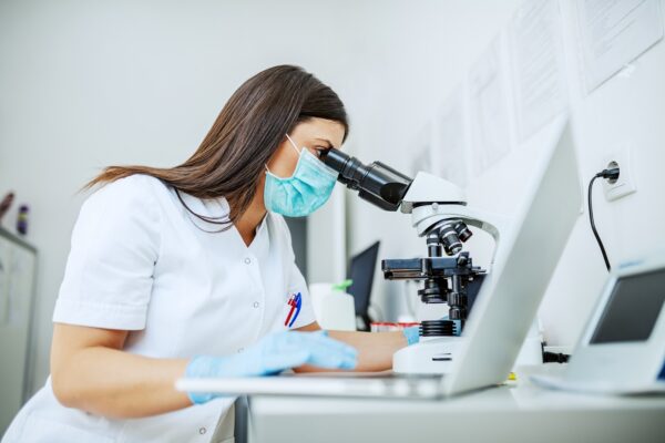 Laboratory assistant looking at sample using a microscope